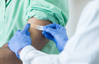 medical professional putting bandaid on arm after getting a flu shot